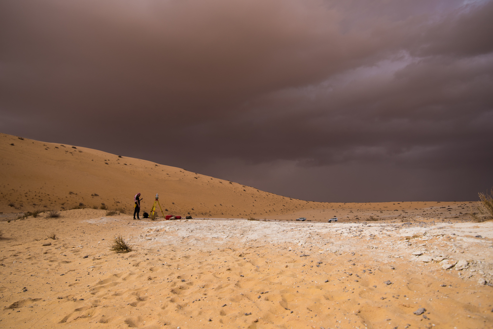 Archaeologists surveying the Al Wusta dig site in the Nefud Desert under dramatic skies